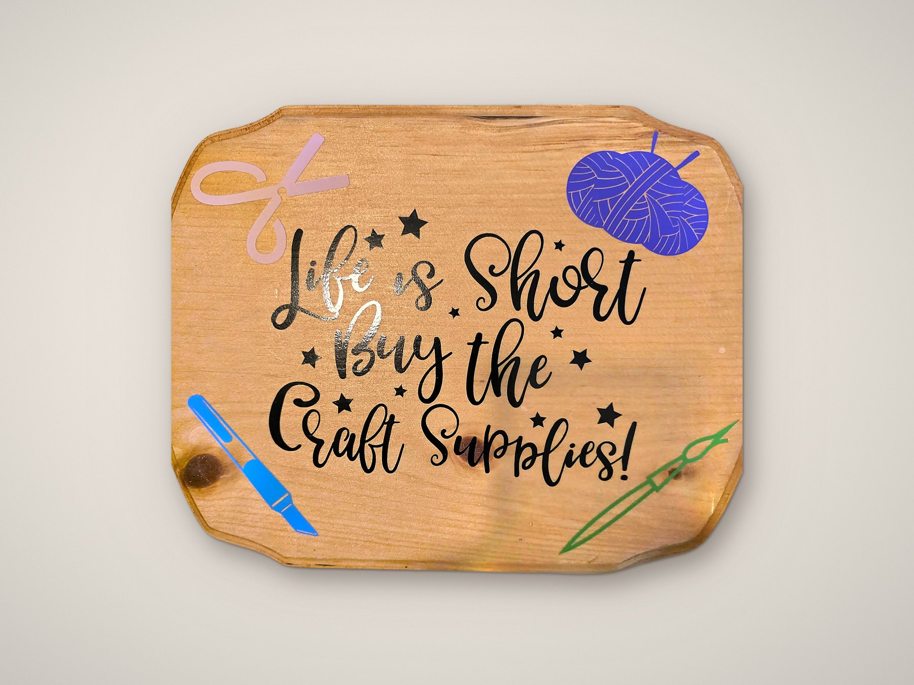 Life is short, buy the craft supplies wood sign on a plain studio backdrop