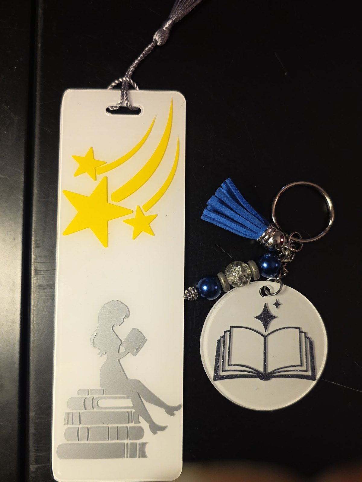 The back of the set: a reader on a stack of books under shooting stars, and an open book keychain